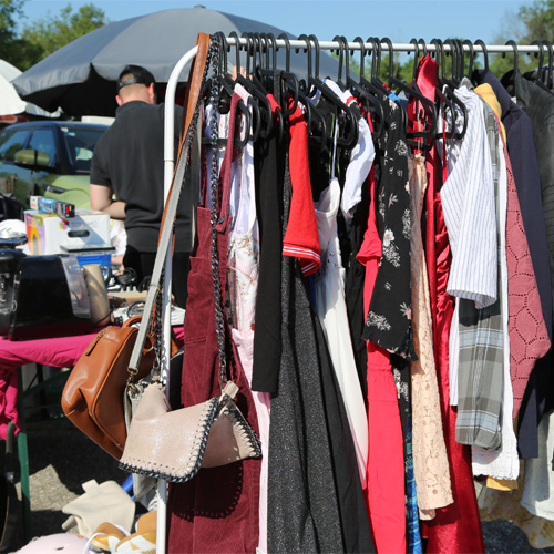 Foto, wo auf Kleiderständer Kleidung am Flohmarkt verkauft wird